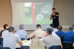 Palestrante apresenta conceitos de gestão comercial e metas para equipe em treinamento corporativo, com slide explicando variáveis que influenciam resultados de vendas.