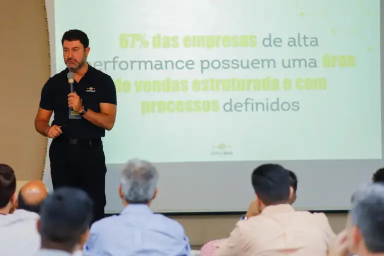 Palestrante apresenta conceito de gestão de vendas estruturada em evento corporativo, mostrando dados sobre processos comerciais e performance para equipe empresarial.