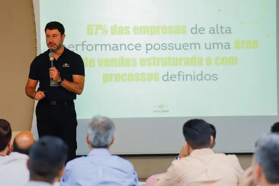 Palestrante apresenta conceito de gestão de vendas estruturada em evento corporativo, mostrando dados sobre processos comerciais e performance para equipe empresarial.