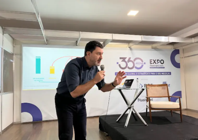 Palestrante apresenta estratégias de pitch de vendas e conversão comercial em evento empresarial, utilizando microfone e projeção de slides ao fundo.