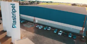 Vista aérea do centro de distribuição da Plastripel, com galpão industrial e estacionamento de veículos em área operacional.