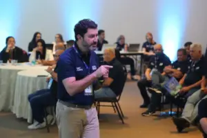Consultor realizando treinamento comercial e alinhamento estratégico com equipe de vendas durante evento corporativo da JointBee.